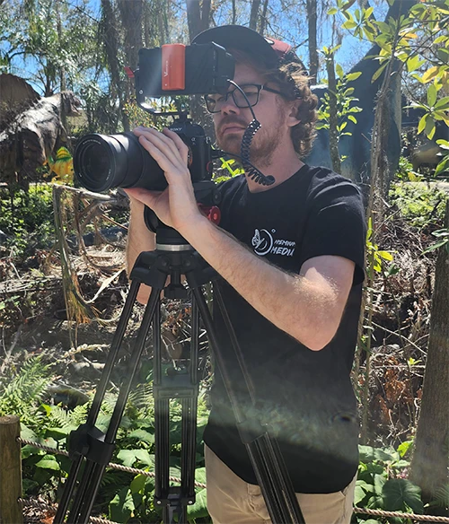 Dallas standing behind a camera on location
