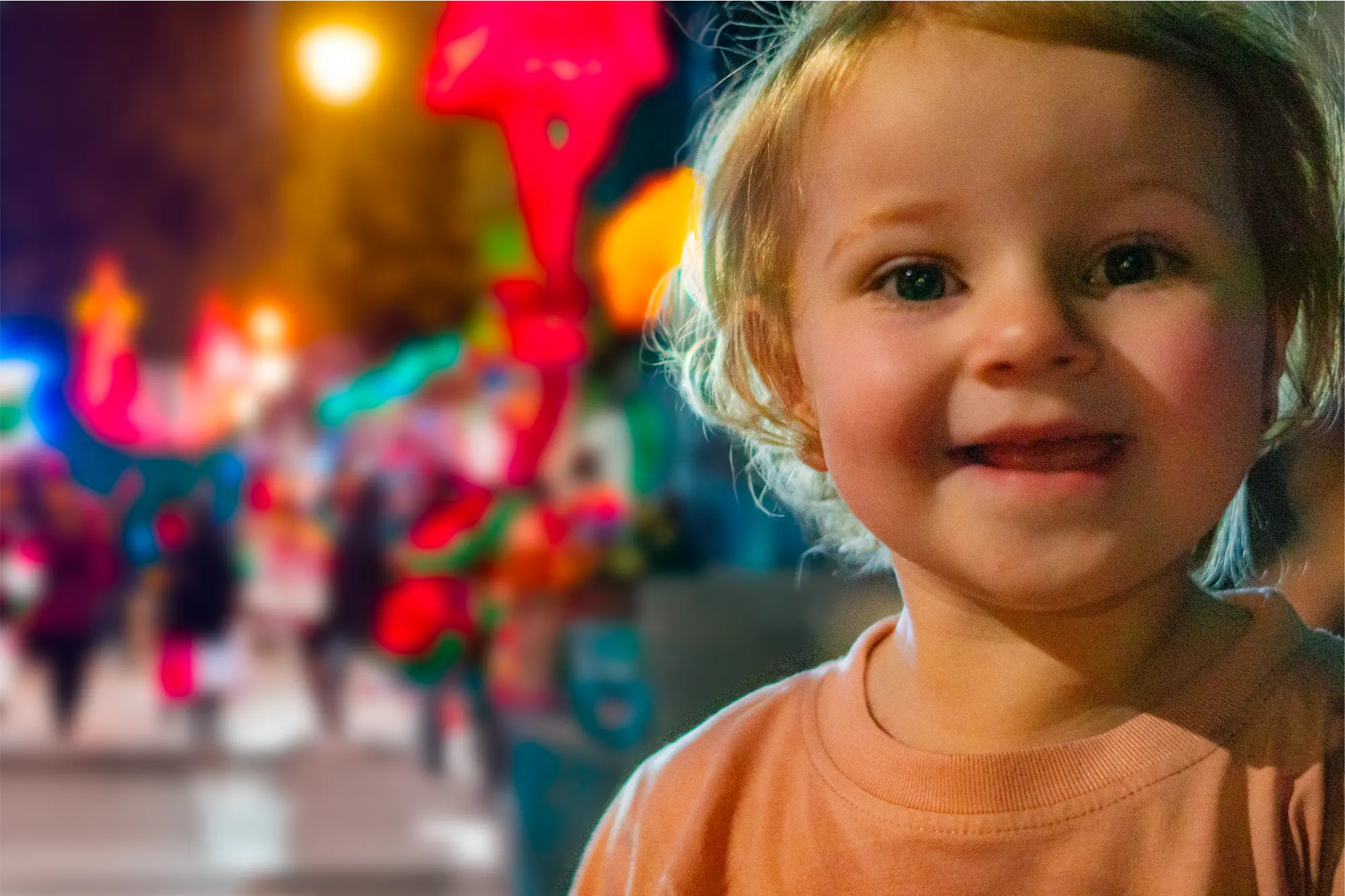 A young girl in front of holiday lights at a parade